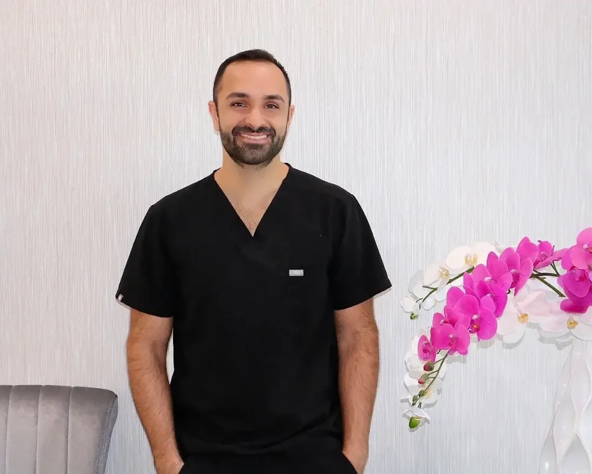 Dr. Edmond Ahdoot standing beside orchids at Smiles by Eddie